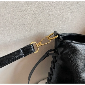 Detail von goldenem Metalldrehverschluss und gewebter Lederstruktur auf schwarzer Tasche