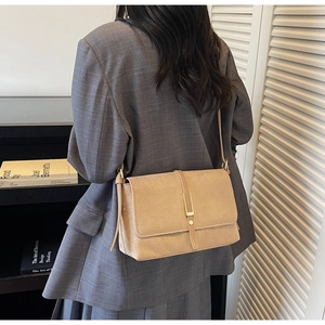 Detail of light coffee crossbody bag with gold buckle on casual gray blazer outfit