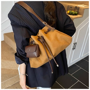 Detail of ginger suede drawstring bucket bag with mini pouch on black blazer model