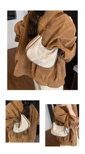 Détail du sac sous le bras en daim beige avec bordure en cuir marron et boucle dorée