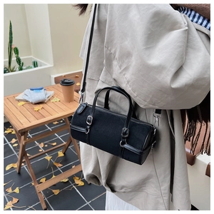 Detailed view of black cylindrical Boston bag with leather patchwork and silver hardware
