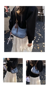 Sac hobo en denim bleu avec garniture en cuir marron et pendentif rond en métal doré