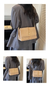 Detailed view of light brown suede shoulder bag with gold buckle on a grey suit model