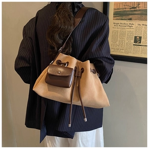Detail of khaki suede bucket bag with brown leather straps shown on a model