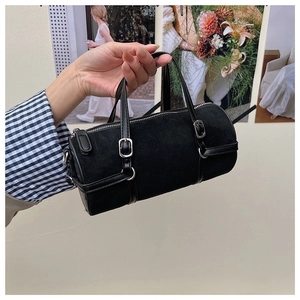 Detailed view of a black suede cylinder bag featuring silver buckles and leather straps
