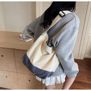 Détail de la sangle noire réglable et boucle sur un sac cabas en toile contrastée