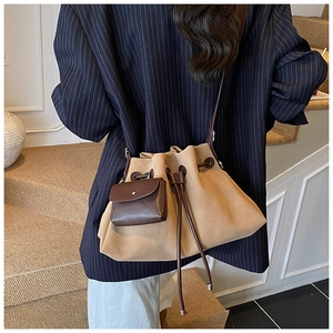 Detail of beige drawstring bucket bag with brown mini pouch and slim shoulder strap