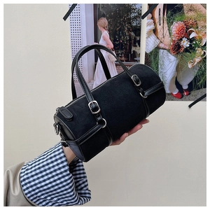 Detail of a black matte suede cylinder bag with leather straps and silver metal buckle