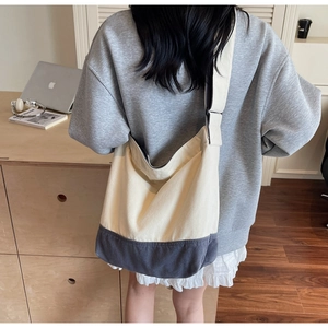 Vue détaillée d'un grand sac cabas en toile bicolore porté à l'épaule par un mannequin