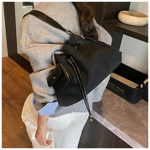 Detail of black canvas drawstring bag with leather strap and snap flap pocket side view
