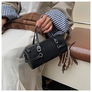 Close-up of minimalist black matte cylinder bag with silver metal buckles and top handles