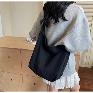 Vue latérale du grand sac cabas en toile noire porté par un mannequin au style décontracté