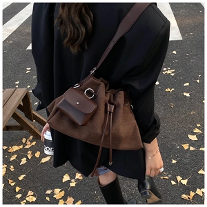 Detail of a dark brown large cloud crossbody bag with a small matching charm pouch