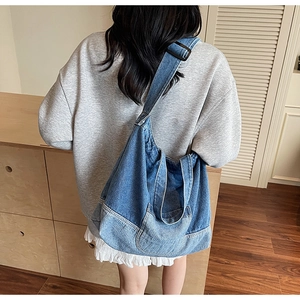 Détail du grand sac hobo rétro en denim porté par un mannequin pour un look décontracté