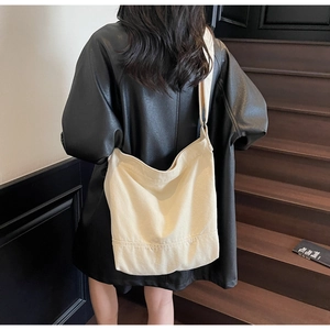 Détail d'un sac cabas en toile durable porté à l'épaule sur un escalier en bois foncé