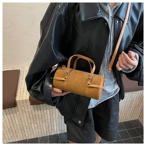 Minimalist brown cylindrical PU handbag shown with strap details in lifestyle photo