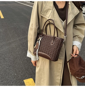 Detailed view of dark brown woven tote bag featuring a creative chocolate charm accessory