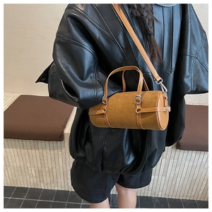 Detailed close-up of a caramel cylindrical handbag with adjustable strap on a model