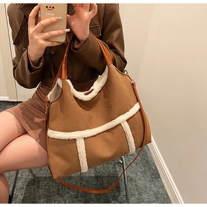 Detail view of large brown suede tote bag with white faux fur trim and leather handles