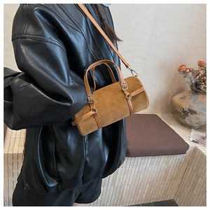 Brown suede cylinder bag with leather straps shown on a model in a retro style
