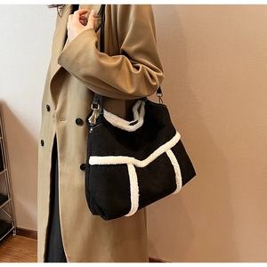 Detail of a large black suede tote bag with white faux fur trim and long shoulder strap