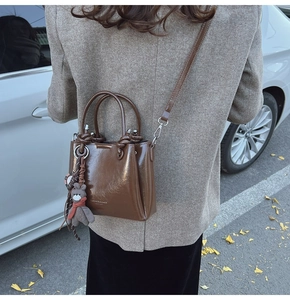 Dettaglio borsa a secchiello vintage in pelle PU marrone con ciondolo a orsetto