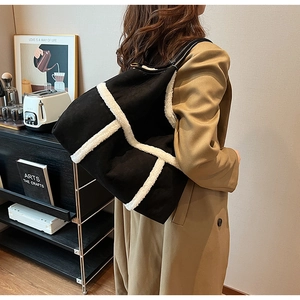 Detail showing contrast shearling trim and matte suede texture on the large black tote bag