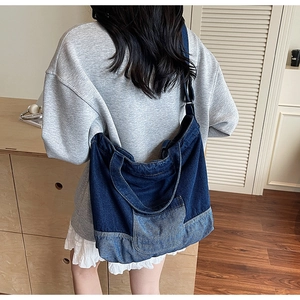 Gros plan d'un grand sac cabas en denim vintage avec empiècements porté à l'épaule