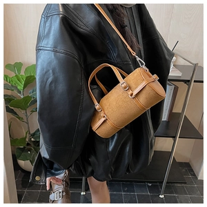 Brown cylinder handbag with adjustable strap shown in a high-quality fashion lifestyle shot