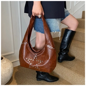 Detail of caramel faux leather bag with silver metal rivets in star pattern decoration