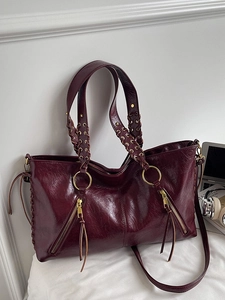 Retro burgunderrote Ledertasche mit geflochtenen Griffen und goldenen Details im Büro