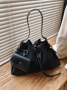 Minimalist black drawstring bucket bag with mini pouch on wooden table with sunlight