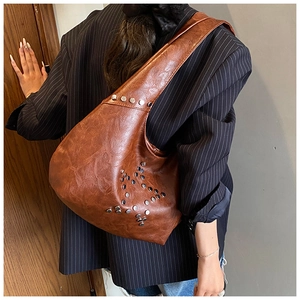 Detail of vintage brown leather hobo bag with silver rivets and distressed texture