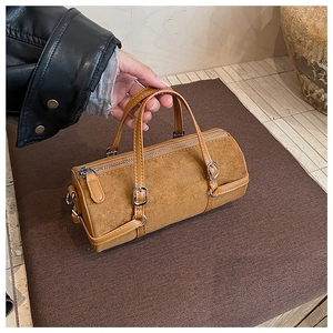 Detailed macro view of the vintage brown cylindrical bag with matte texture and buckle