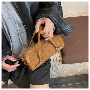 Close-up of brown suede cylinder handbag with leather handles and silver hardware