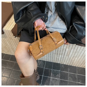 Close-up of brown suede cylinder bag with silver buckles and leather handles