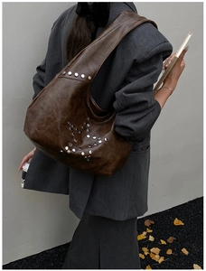 Detail of dark brown vintage faux leather tote with silver star-shaped rivet studs