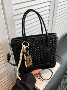 Chic black quilted bucket bag with woven texture and chocolate-shaped charm detail