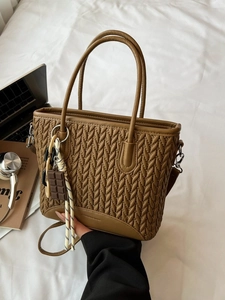 Brown quilted crossbody bucket bag with V-shaped stitching and a chocolate charm
