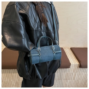 Blue cylindrical shoulder bag styled with a black leather jacket on a model