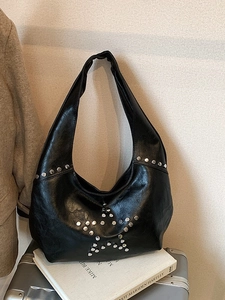 Vintage black leather hobo shoulder bag with silver rivet star patterns on a white background