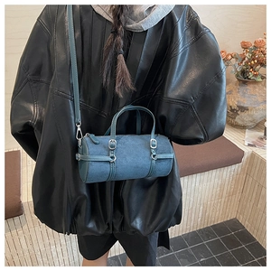 Detail of blue-grey cylindrical Boston bag with matte finish on a female model
