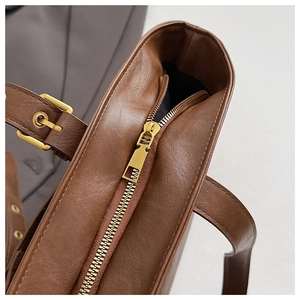 Detailed macro view of dark coffee tote bag with lychee texture and golden zipper