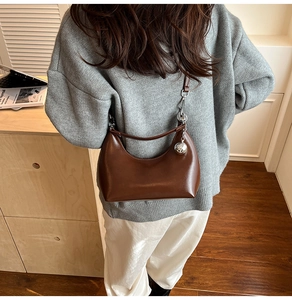 Detail of dark brown leather hobo bag with silver ball charm on model back in home setting