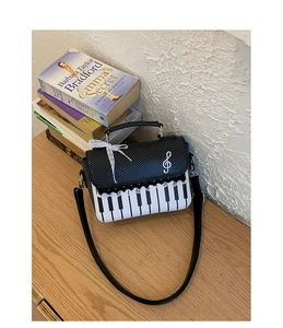 Detail of piano key handbag with polka dot flap and music note on a wooden table