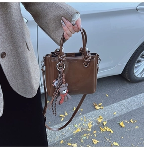 Dettaglio della borsa a secchiello vintage in pelle cerata marrone con ciondolo a orso