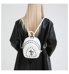 Détail du mini sac à dos blanc avec croix métallique rétro et ornements de rivets argent