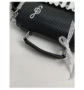 Detail of polka dot handbag with lace bow and embroidered musical note motif