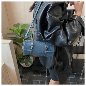 Detail of blue suede cylinder bag with silver metal buckle and textured leather strap
