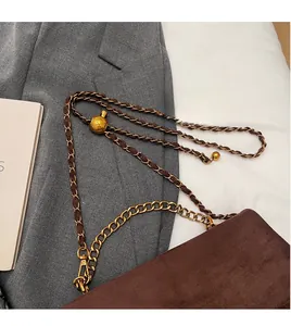 Detail of brown suede shoulder bag featuring adjustable gold metal chain and ball charm
